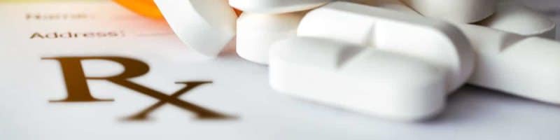 Photo of a pile of nondescript white pills on an unfilled prescription form