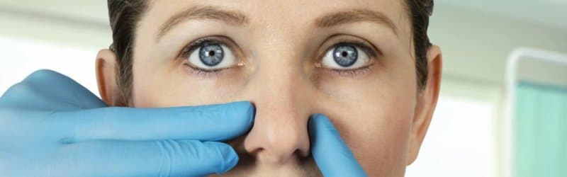 Photo of a person whose nose is being pushed by gloved hands