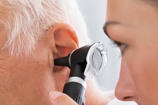 An audiologist inspecting a patient with an otoscope