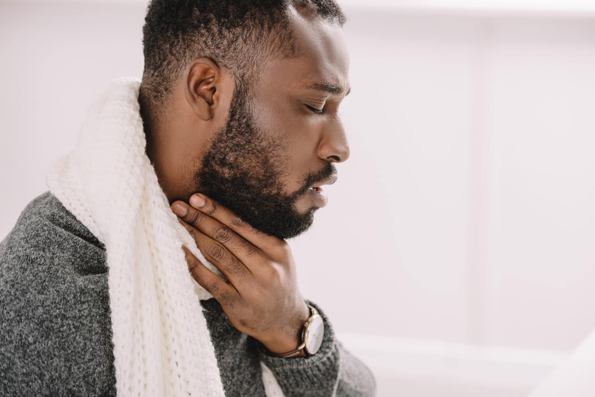 ent - throat Photo of a person wearing a scarf but holding their neck in pain