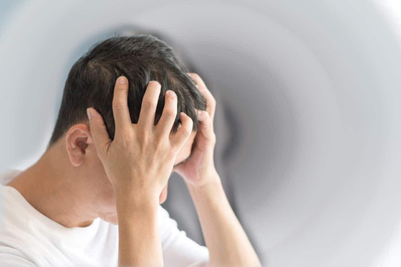 Photo of a person holding their head in both hands in distress