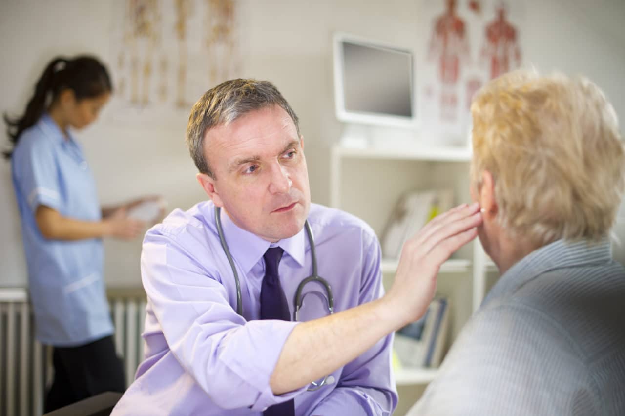 Photo of a provider reaching out and touching the ear of a patient