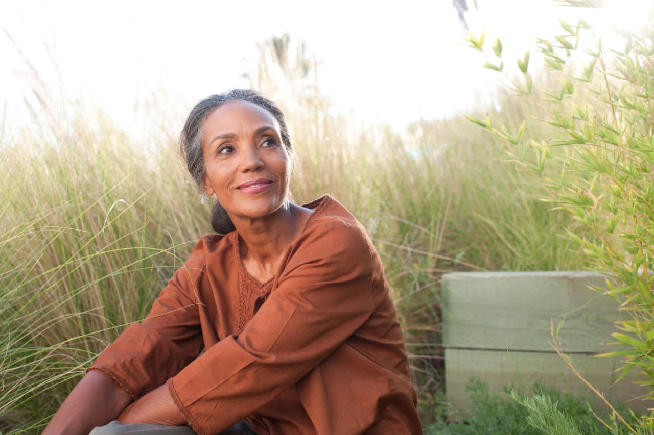 Photo of a person looking peaceful and sitting in a field of tall grasses