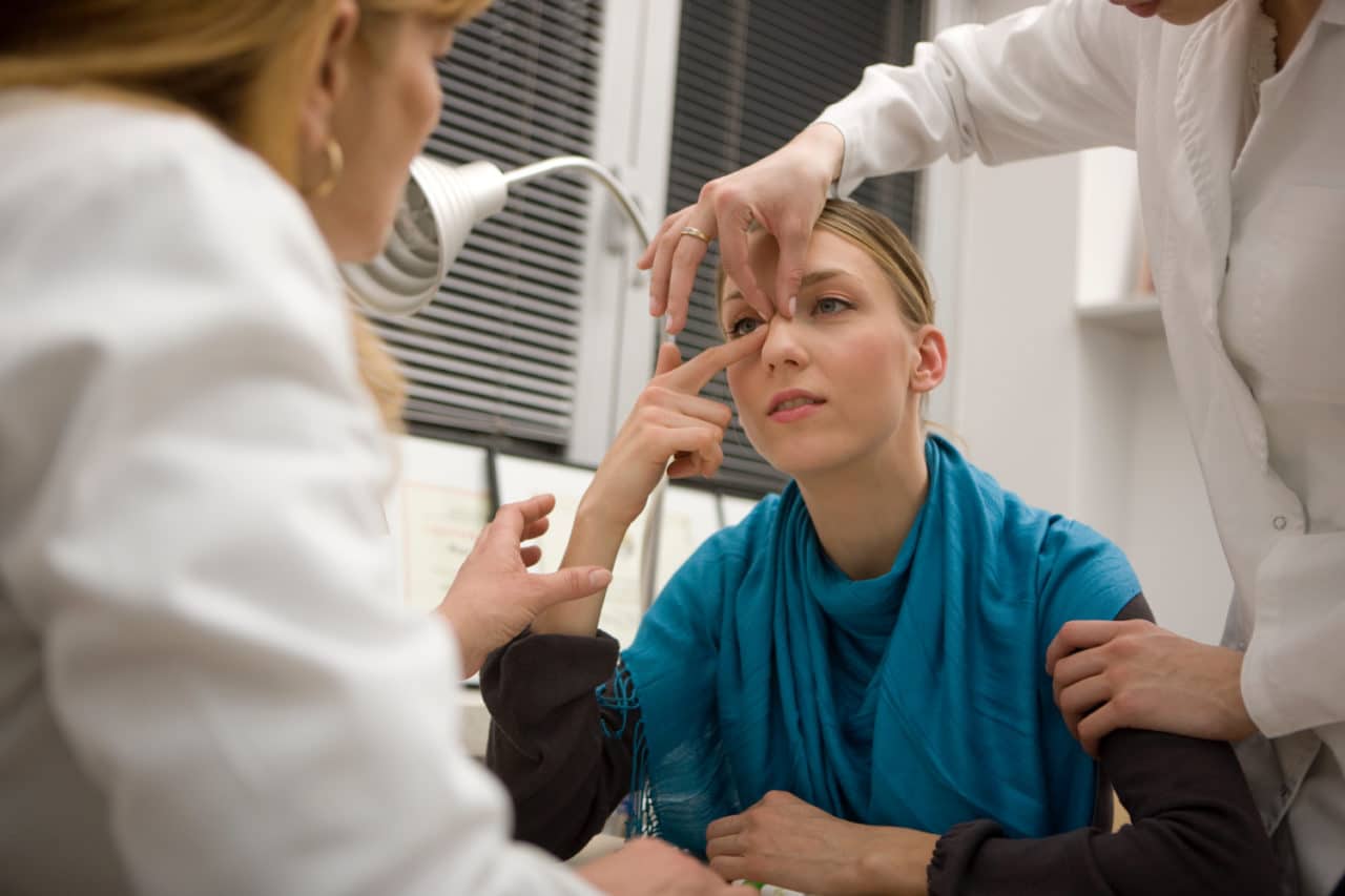 A patient in consultation with two health care providers, all pointing at the former's nose