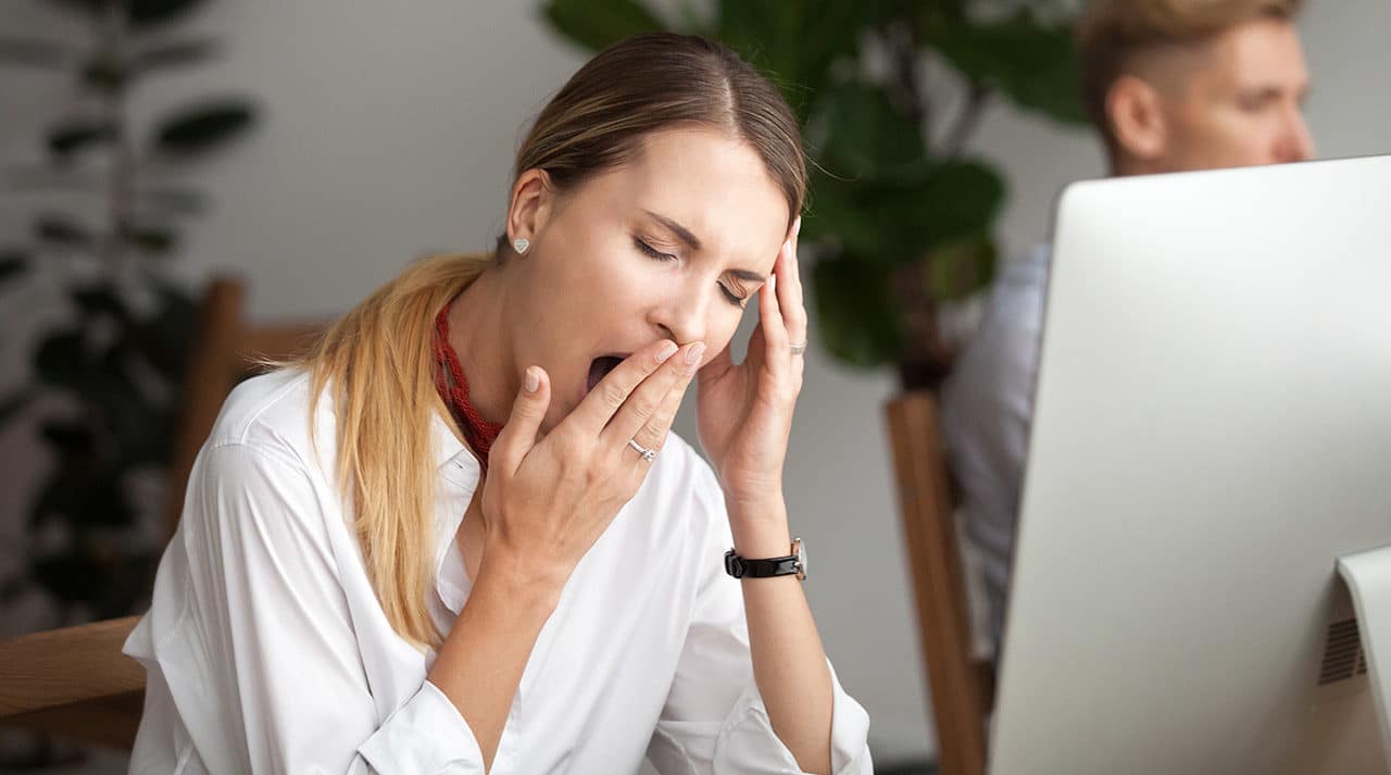 Photo of a person sitting at a desk and covering a yawn