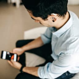 Man with hearing aids looking at phone in hotel room