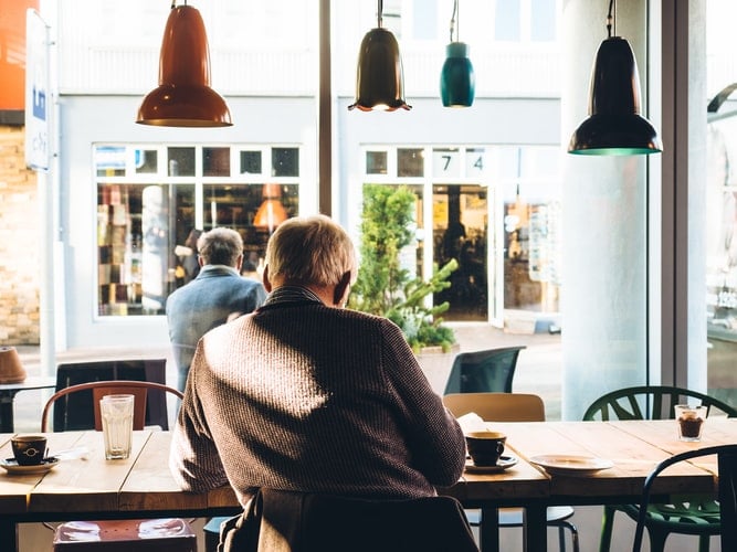 The Difference Between Hearing Aids and Cochlear Implants Man sitting inside coffee shop
