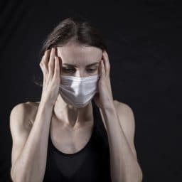 Woman with a headache wearing a mask.