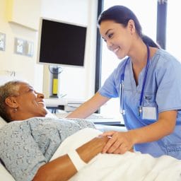 Nurse checking in on older female patient after surgery.