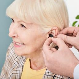 Smiling senior woman getting fitted for a hearing aid.