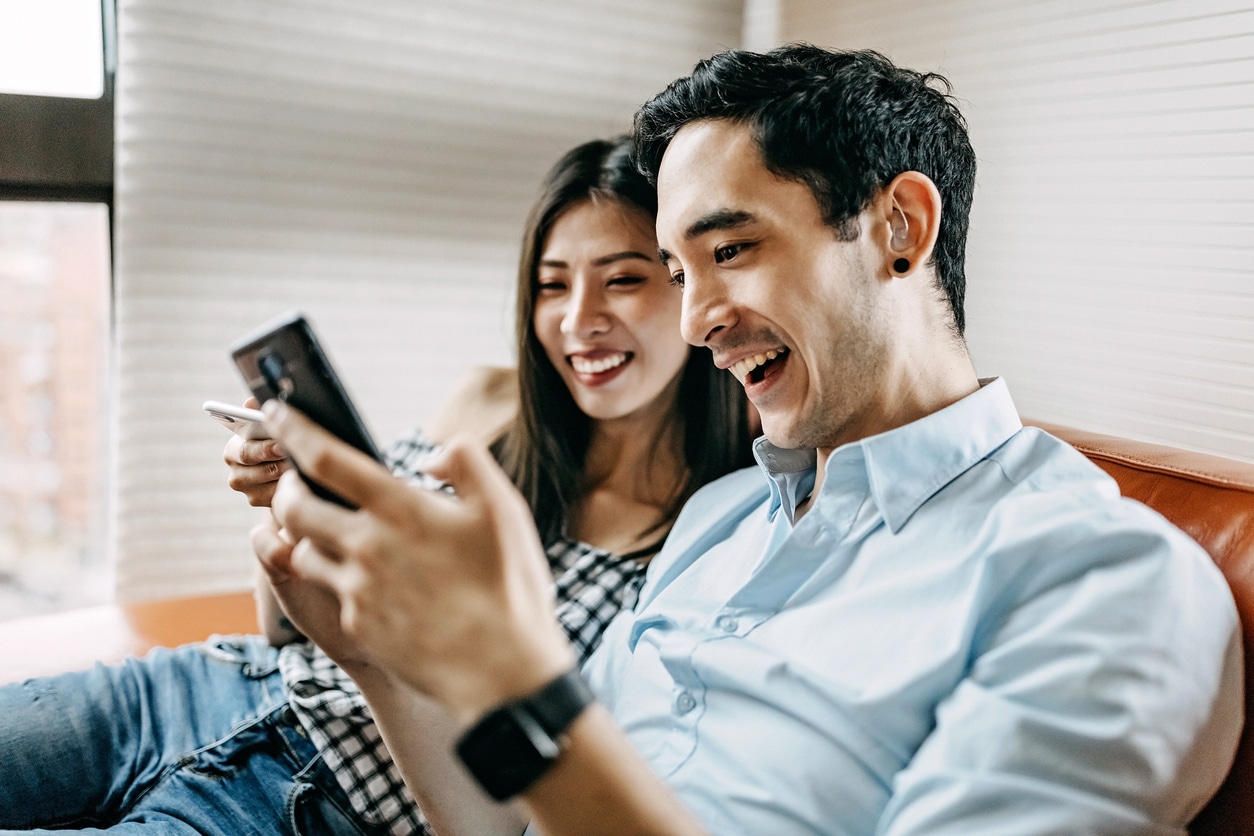 Man wearing a hearing aid sitting on a couch with his girlfriend.