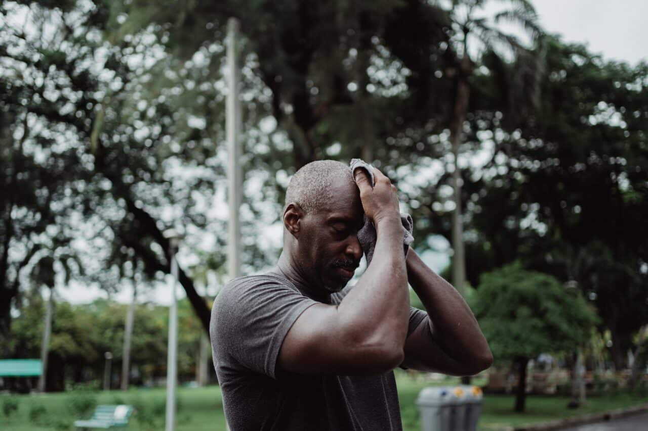 Senior man wiping his brow after exercising in the summer heat.