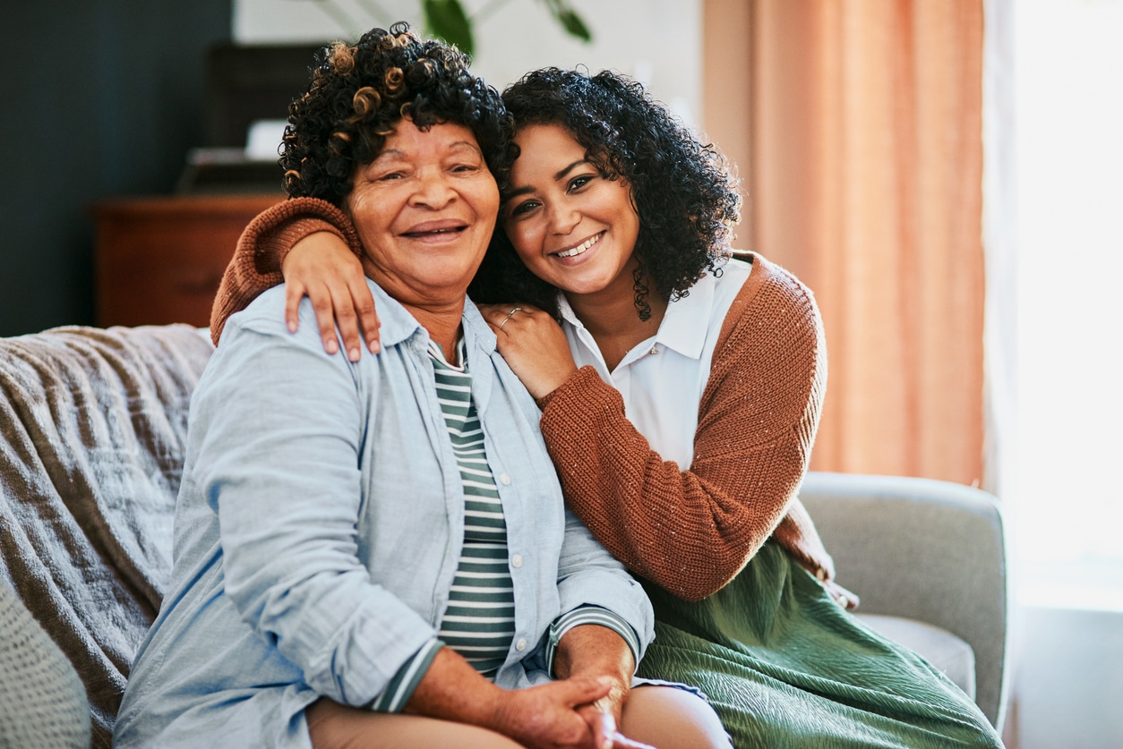 Daughter hugging her mom on the couch.