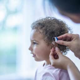 Provider putting a hearing aid in a young girl's ear