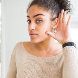 Woman with her hand to her ear trying to listen
