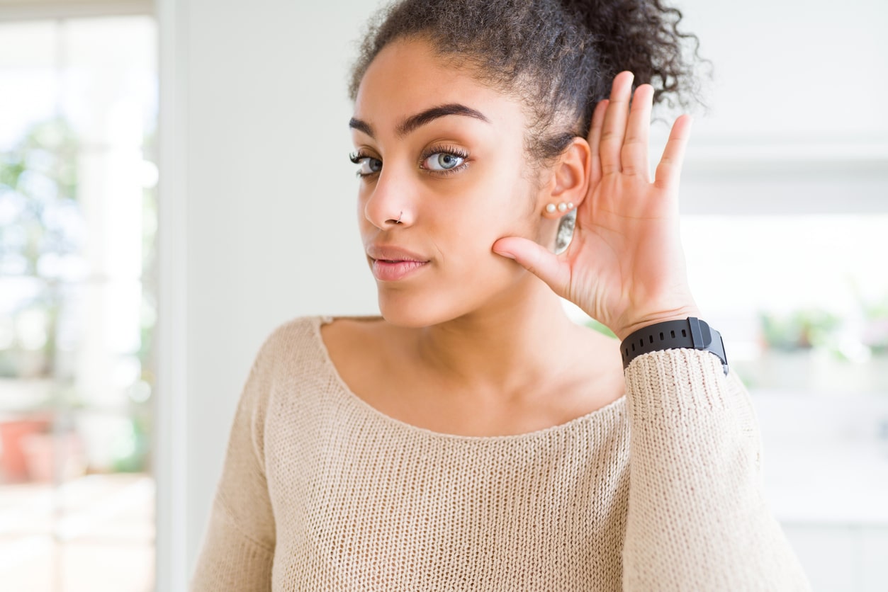 Woman with her hand to her ear trying to listen.