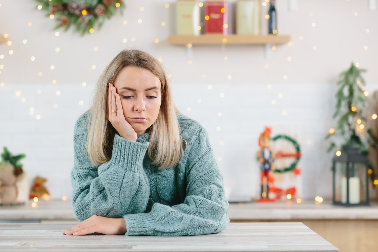 Young woman looking stressed at a table with holiday decorations behind her