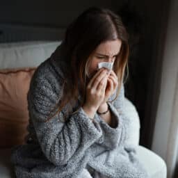 Woman with a cold blowing her nose.