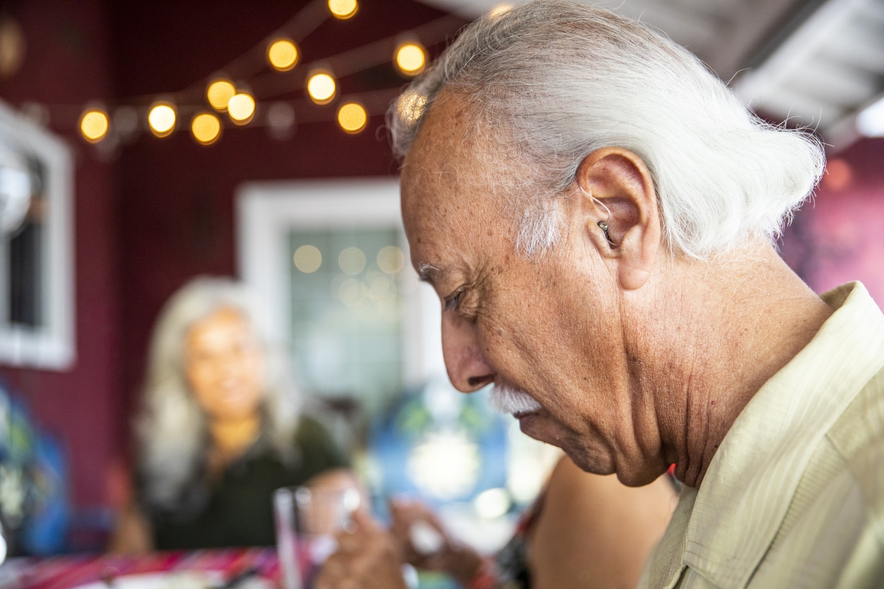 Senior man wearing a hearing aid at dinner.