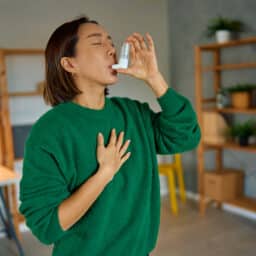 Woman at home reaching for an inhaler during an asthma attack.